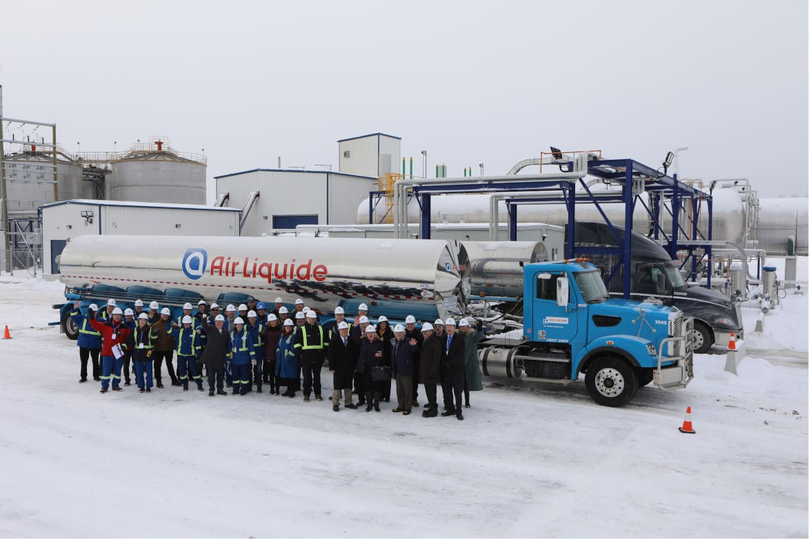 Smiling group of Air Liquide employees posing for a photo in front of company trucks at the Johnstown, Ontario site.